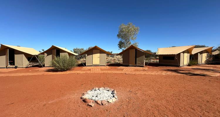 Hébergement sous tente avec un foyer dans un paysage désertique.