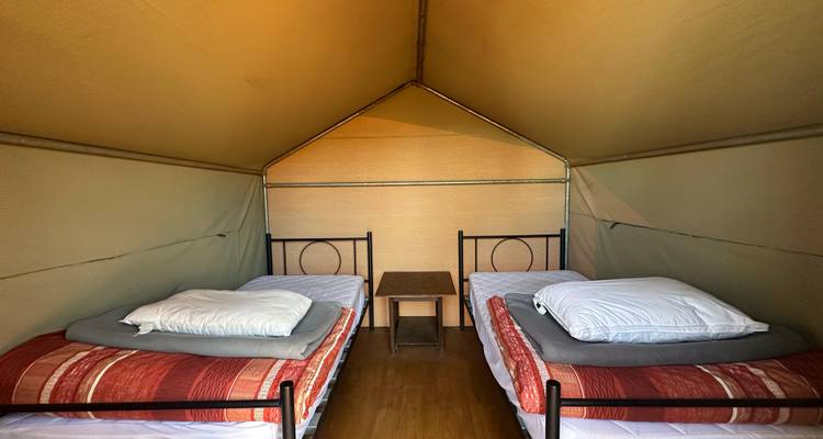 Intérieur d'une tente avec deux lits et des oreillers.