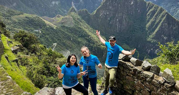 Touristen posieren mit Berg und Ruinen im Hintergrund.