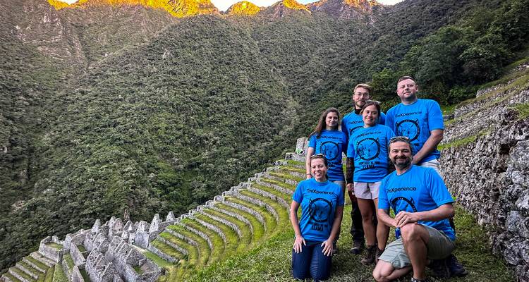 Gruppe von Menschen, die vor terrassierten Bergen bei Sonnenuntergang posiert.