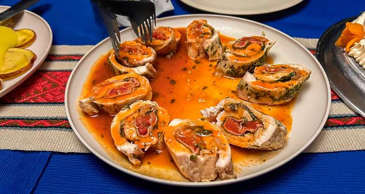 Teller mit aufgerollten Fleischscheiben mit Sauce auf einer bunten Tischdecke.