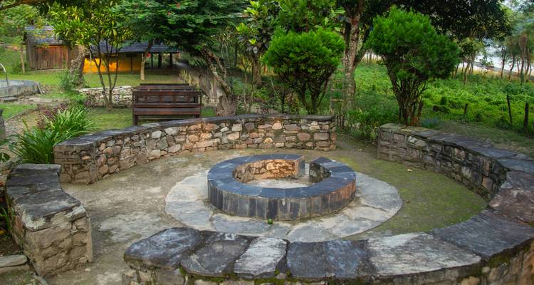 Fogata circular de piedra con muros de asiento en un claro rústico de campamento