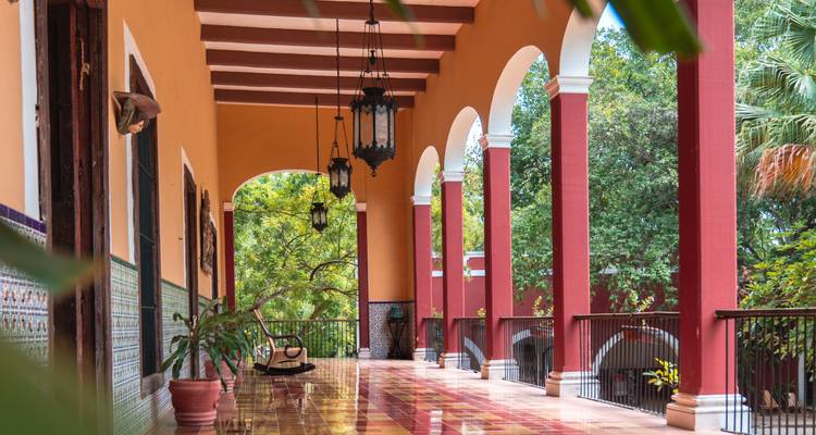 Corredor elegante de hacienda con pisos de azulejos, arcos y linternas colgantes.