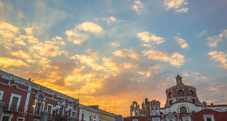Les toits coloniaux et le dôme de l'église illuminés par les ciels du coucher de soleil colorés à Puebla.