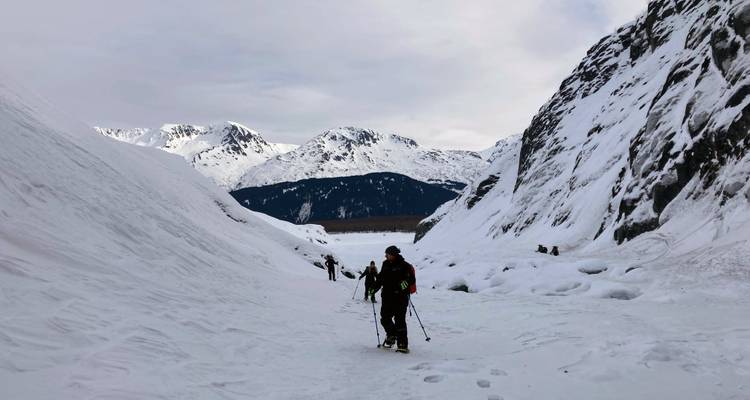 Wandelaars die door een besneeuwde bergpas lopen.