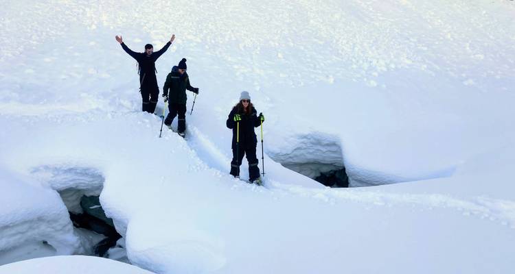 Menschen wandelen op sneeuw in bergachtig terrein.