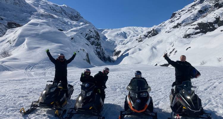 Groep sneeuwscooterrijders die feest vieren in een besneeuwde kloof.