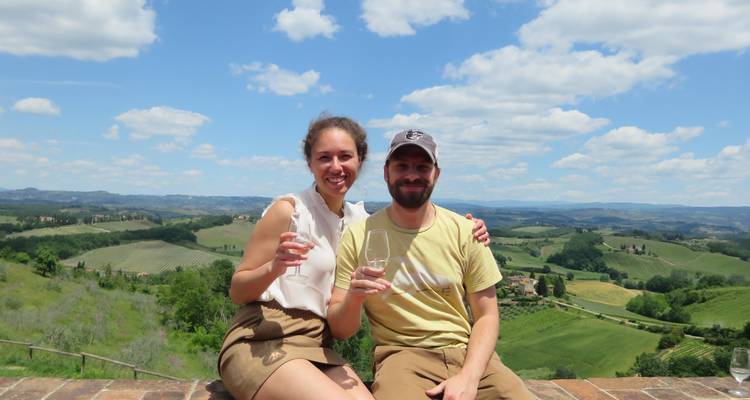 Pareja disfrutando vino con una vista panorámica de las colinas toscanas.
