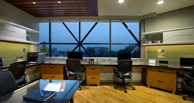 Espace de travail de bureau moderne avec des bureaux, des ordinateurs et une vue sur la ville à travers des fenêtres géométriques.