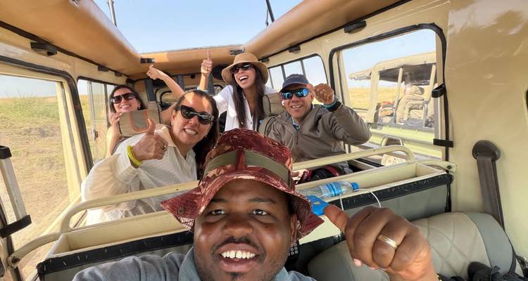 Viajeros felices en safari dando pulgar hacia arriba dentro de una jeep de techo abierto en la sabana