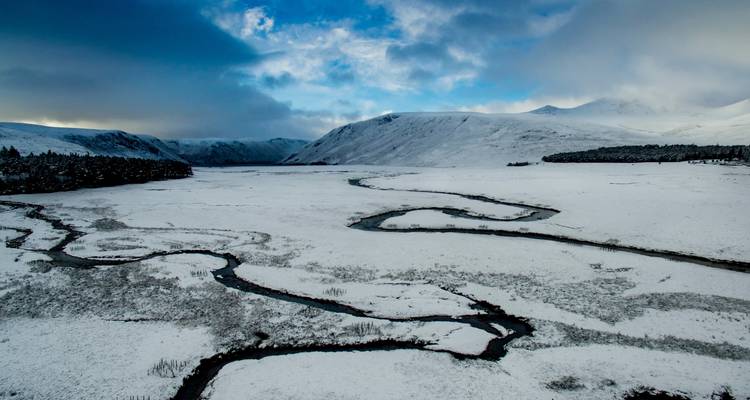 Luchtfoto van een met sneeuw bedekt landschap met een kronkelende rivier.