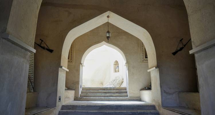 Arco de piedra y escalones que conducen al interior tranquilo de un antiguo fuerte del desierto.