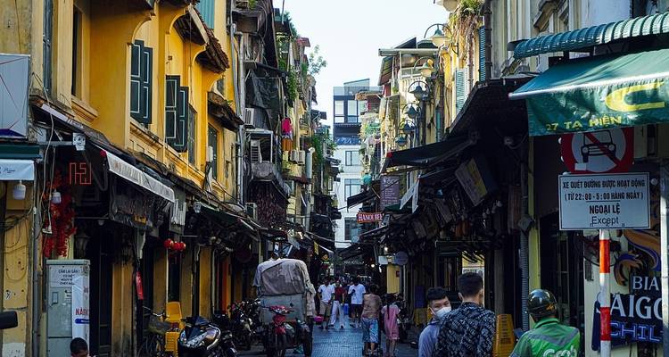 Bustling street in Hanoi's Old Quarter with yellow buildings.