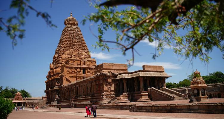 Temple Brihadeeswarar massif avec son vimana imposant sous un ciel bleu, des visiteurs marchant à la base.