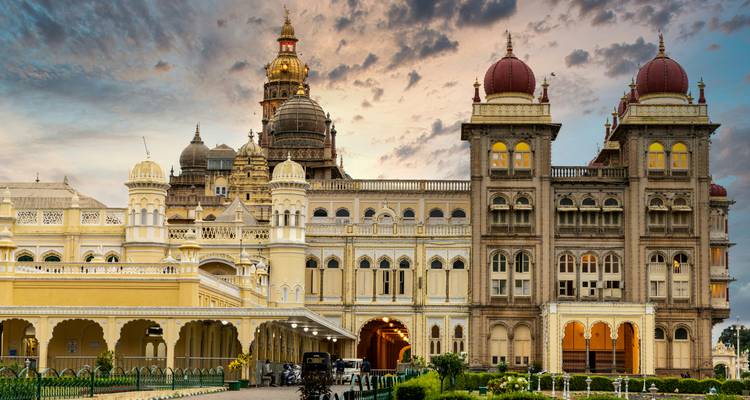 Le Grand Palais de Mysore illuminé par les nuages du coucher de soleil aux tons chauds, avec ses dômes et ses arcs ornés.