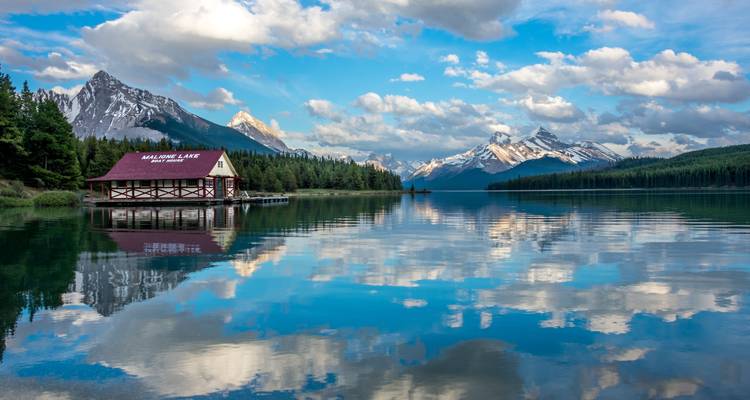 Beau lac avec des reflets de montagnes et un hangar à bateaux.