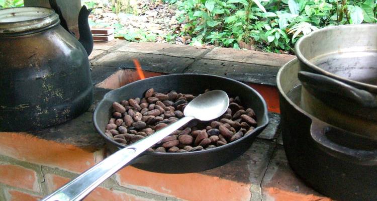 Cacaobonen die roosteren in een pan boven een open vlam.