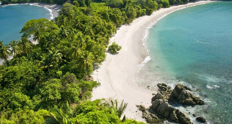 Luchtfoto van een afgelegen strand met turquoise water en wit zand.