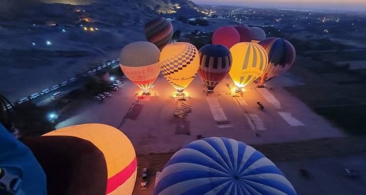 Hot air balloons lit up on the ground at dawn or dusk.