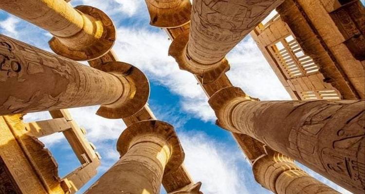 Close-up upward view of ancient stone columns against a blue sky.