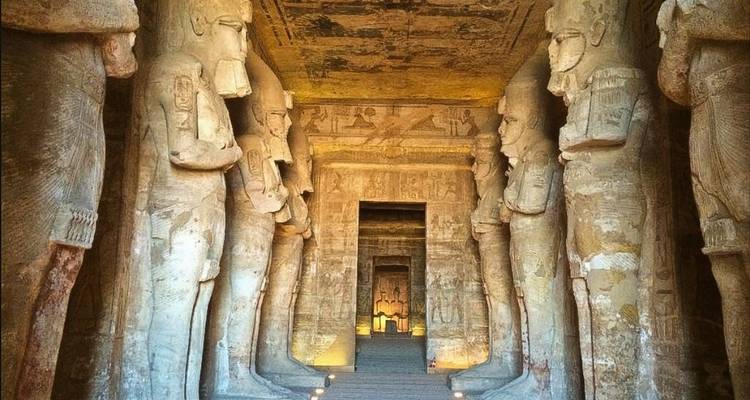 Interior view of an ancient Egyptian temple with statues lining the corridor.