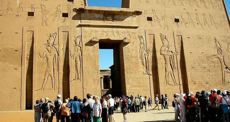 A crowd of tourists visiting the entrance of an ancient Egyptian temple with carvings.