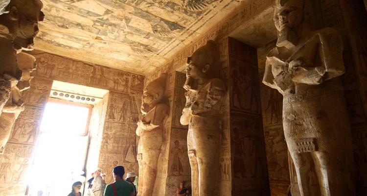 Interior of an Egyptian temple featuring statues and hieroglyphics.