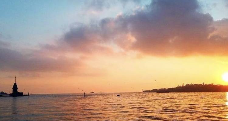 Sunset view over a body of water with distant land on the horizon.
