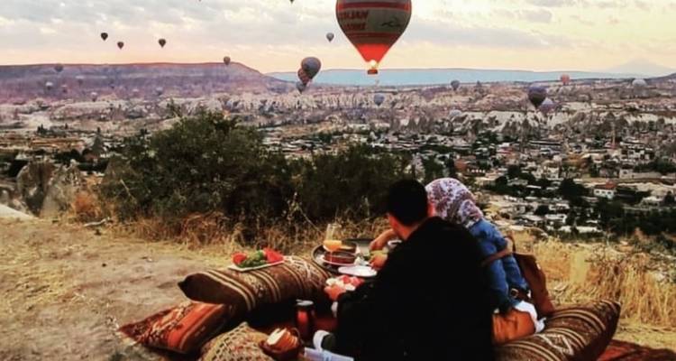 Couple having a picnic while watching hot air balloons.