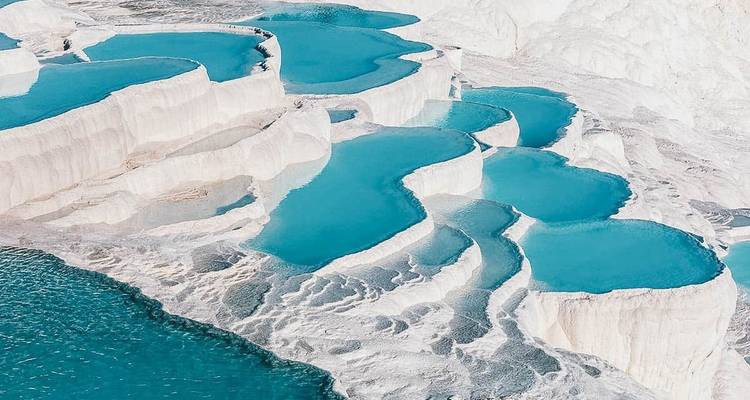 White, terraced mineral pools filled with blue water.
