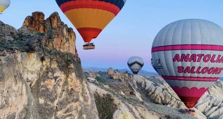 Hot air balloons flying over rocky cliffs.