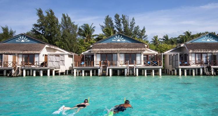 People snorkeling near overwater villas.