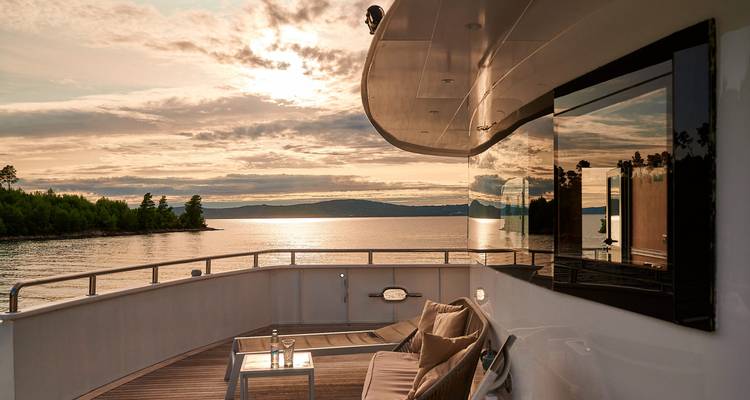 Blick auf ein Yachtdeck bei Sonnenuntergang mit ruhigem Wasser.