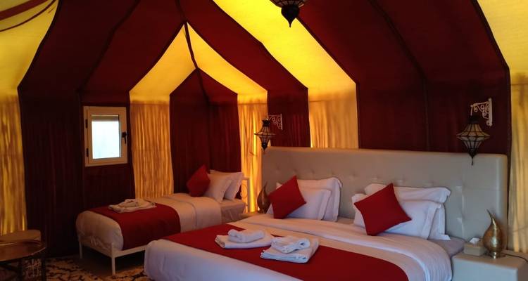 Interior of a luxurious tent with beds and furnishings.
