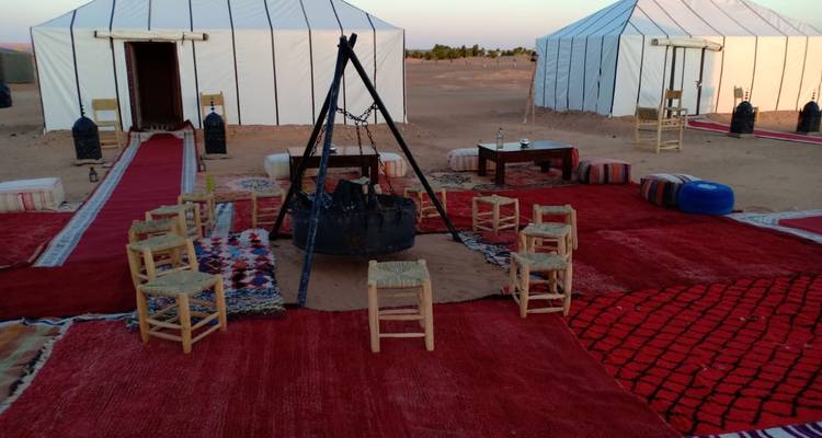 Campsite in the desert with fire pit and surrounding tents.