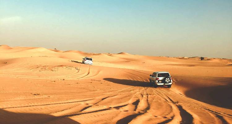 SUVs conduciendo sobre dunas de arena en un desierto.