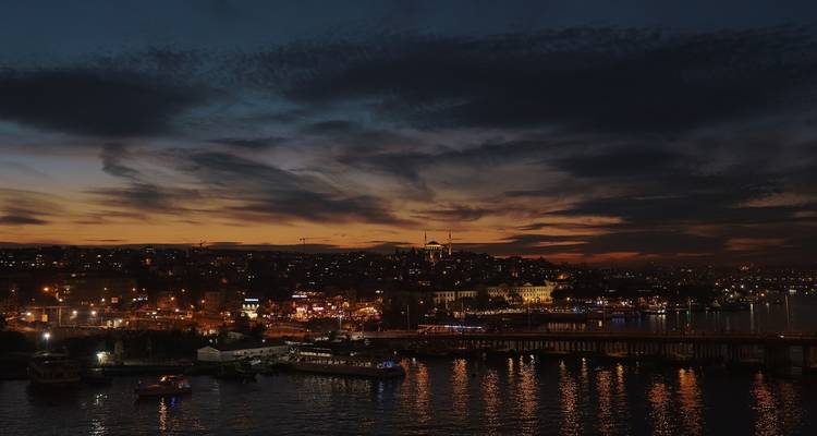 Stadslichten die reflecteren op het water bij zonsondergang in Istanbul.