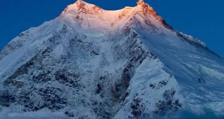 Sneeuwbedekte bergtop die gloeit onder het vroege zonlicht.