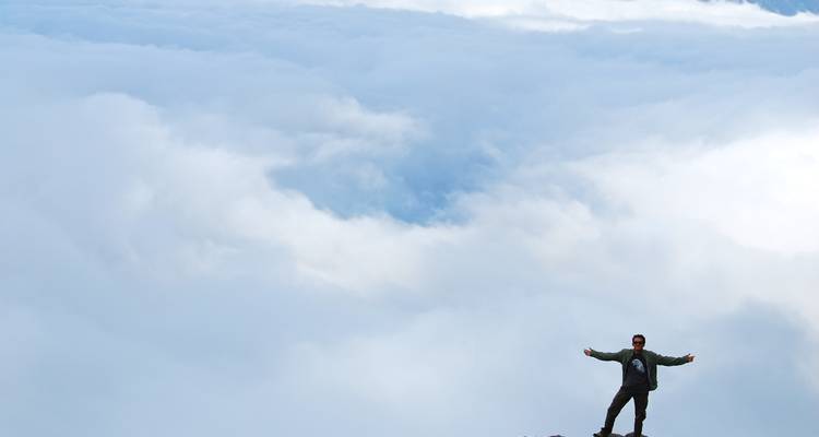 Man standing on a peak above the clouds.
