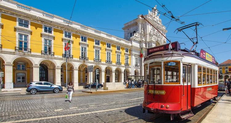 Rote Straßenbahn und gelbes Gebäude auf einem Stadtplatz.