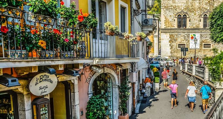 Bunte Straße mit Geschäften und Touristen in Taormina.