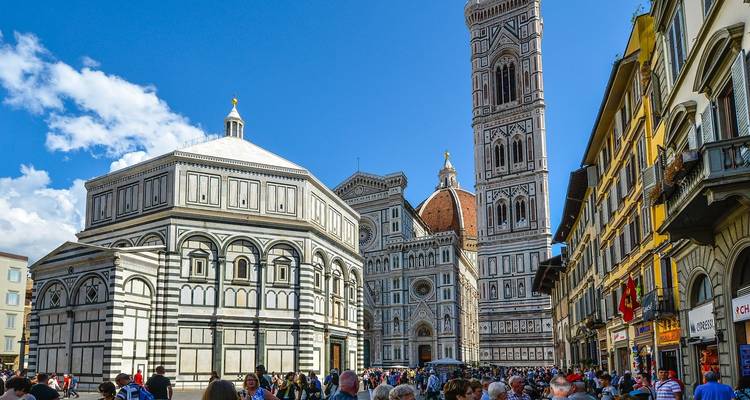Crowded square with historic church buildings and a tall bell tower.