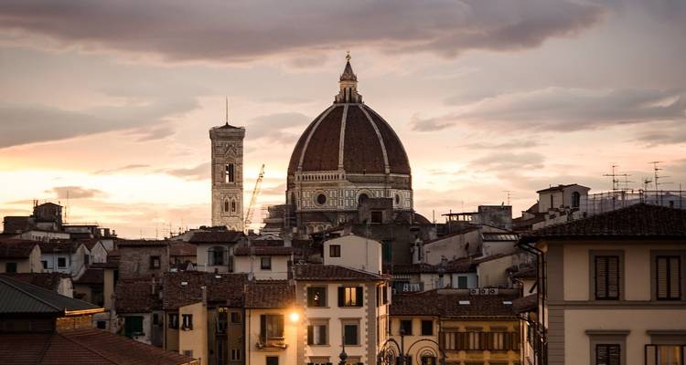 Sunset over rooftops with a prominent cathedral dome.