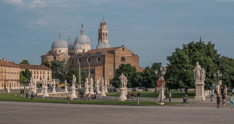 Wide plaza with cathedral and statues under a blue sky.