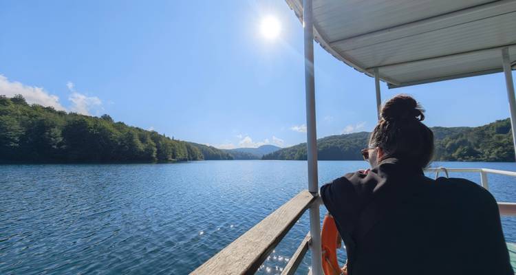 Een persoon die vanuit een boot geniet van het uitzicht op een serene meer.