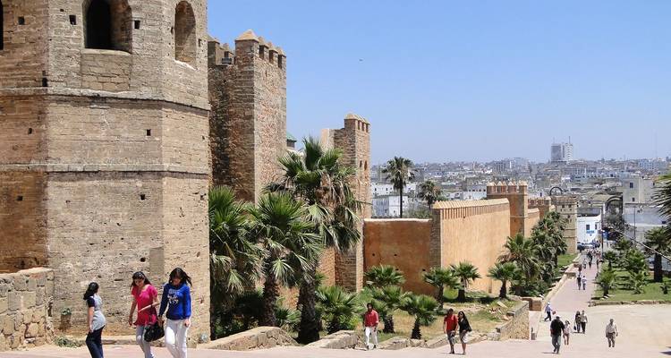 Historische muren met mensen die wandelen in een weelderig tuingebied.