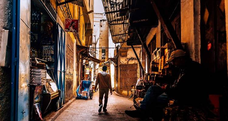 Persoon die door een smalle, traditionele Marokkaanse markt loopt.
