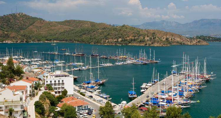 Marina mit zahlreichen angedockten Booten und umliegenden Hügeln.