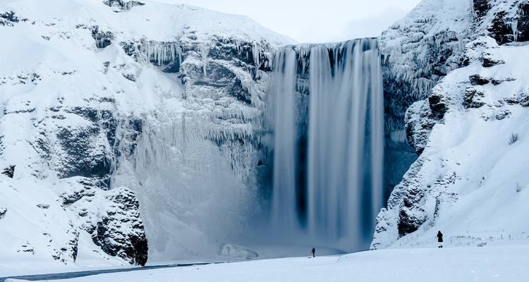 Sneeuwbedekte waterval tegen een winterse achtergrond.