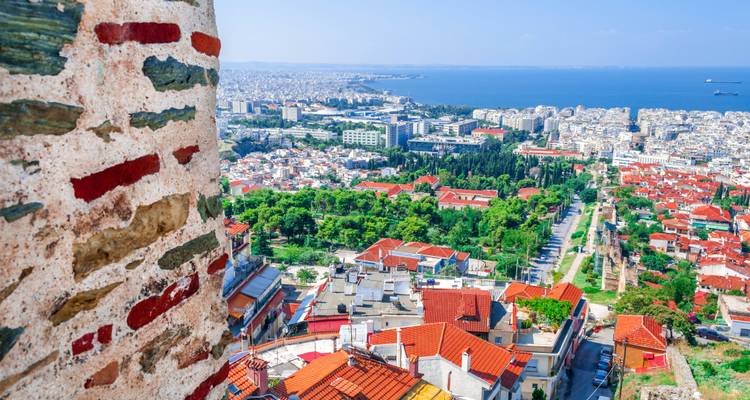 Panoramic vista of Thessaloniki’s red-tiled rooftops and the Aegean Sea from an ancient stone tower.